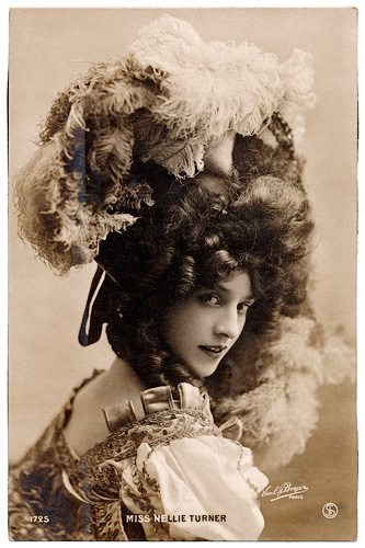 Image of actress with large ruffled hat. She is turning to look at us over her right shoulder. The photo is in sepia.